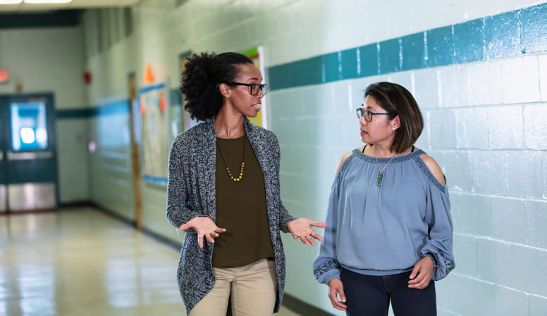 principal and teacher talking in the hallway